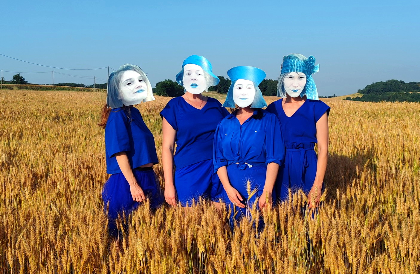 Photo de l'affiche du spectacle Rolls-Royce, quatre femmes vêtues de bleu avec des masques en carton au milieu d'un champs de blé.